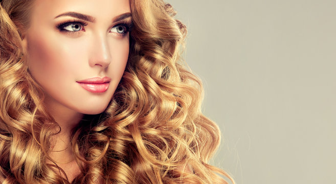 Beautiful girl with long wavy hair . Blonde model with curly hairstyle . 
