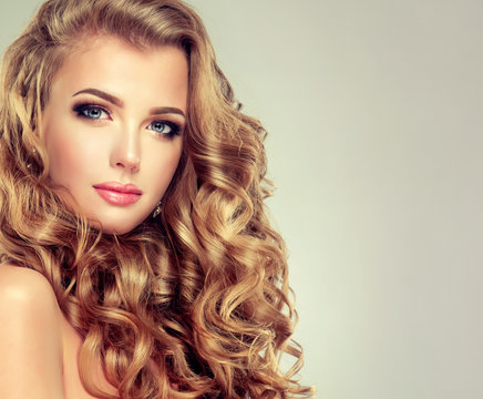 Beautiful girl with long wavy hair . Blonde model with curly hairstyle . 

