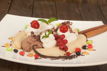 Ice cream sundae, Banana Split with topping, dry fruit, mint leaves and cherry.