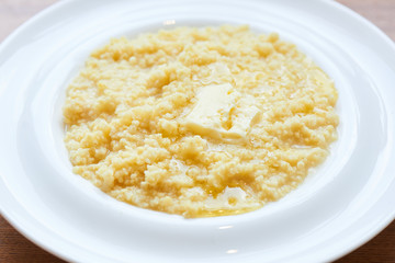 A healthy Breakfast of millet porridge with butter served in a white plate