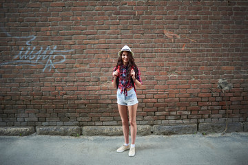 Portrait of a girl tourist in a hat on a background of red brick building