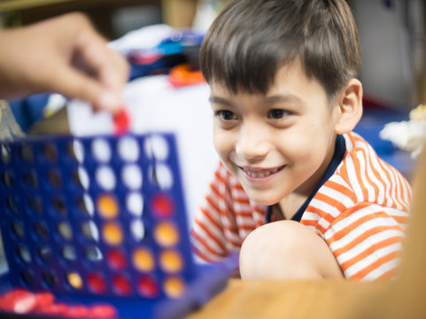 Little Boy Playing Connect Four Game Soft Focus At Eye Contact