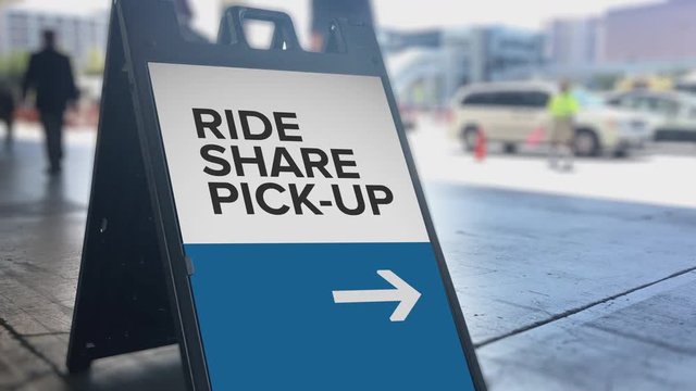 A sign denotes where the official ride sharing pickup location is outside a large convention center.	