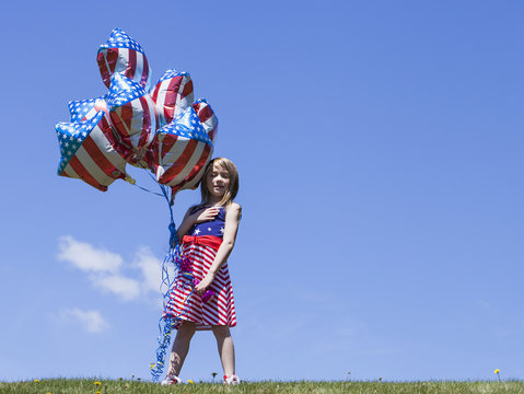 Cheerful American  girl holding balloons outside. 4th of July. Independence day. 