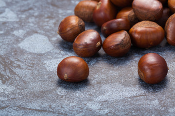 Horizontal image of a pile of chestnuts on stone texture floor with copy space