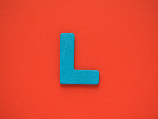 Capital letter L. Blue letter L from wood on red background.