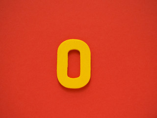 Capital letter O. Yellow letter O from wood on red background. Alphabet vowel.