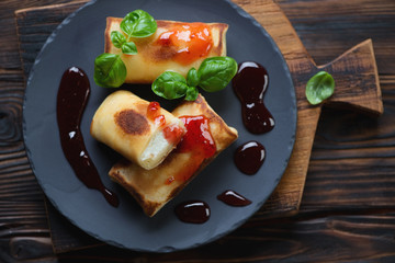 Above view of stuffed rolled crepes served on a basalt plate
