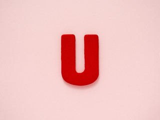 Capital letter U. Red letter U from wood on pink background. Alphabet vowel.