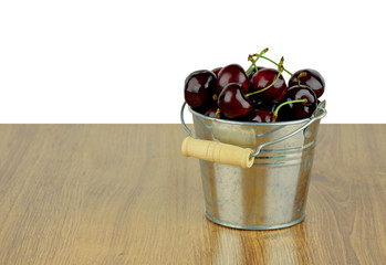 Ripe juicy sweet cherries in a small metal bucket.