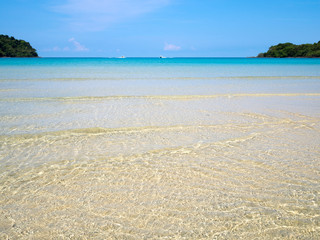 Background of transparent crystal blue sea water surface ripple over sand with sun reflection in summer. Water background. Ocean water texture.