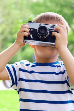 Happy cheerful boy with a camera, the baby photographed outdoors