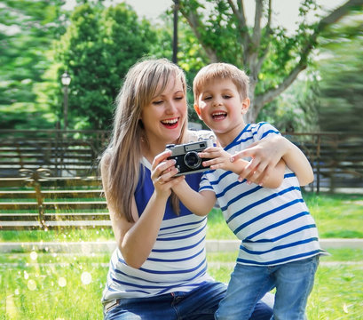 Happy cheerful boy with a camera, the baby photographed outdoors