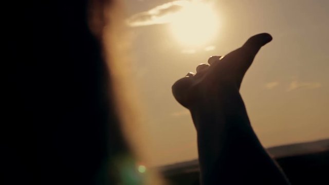Girl looking at the sunset through her hands