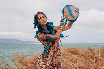 attractive young woman in ethnic jewelry with drum outdoors