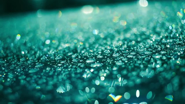 Rain drops on glass surface in aquamarine color. Macro of droplets on glass after rain. Closeup of shiny water drops on glass at night. Water droplets on glass in aquamarine color. Abstract background
