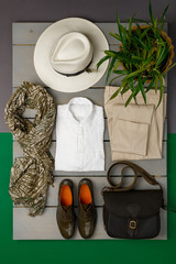 Women's outfit on wooden background. fashion clothes. beige straw hat, beige pant, white shirt,...