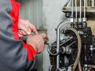 Professional mechanics testing diesel injector in his workshop,