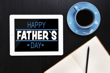 Happy father's day concept. Tablet with cup of coffee and notepad on black wooden table