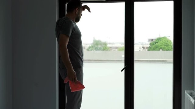 Young, tired man finish cleaning a window at his home

