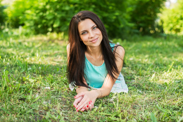Beautiful woman relaxing outdoors on grass looking happy and smiling.