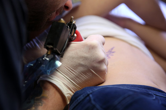 Master doing tattoo on female  body, closeup