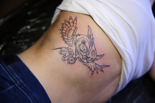 Female body with bird tattoo, closeup
