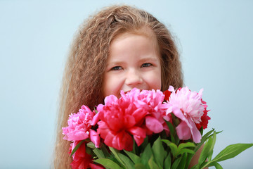 Naklejka premium Girl holding fresh peonies bouquet on blue background