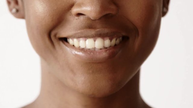 Closeup lips black girl starts smiling, happy showing healthy white teeth