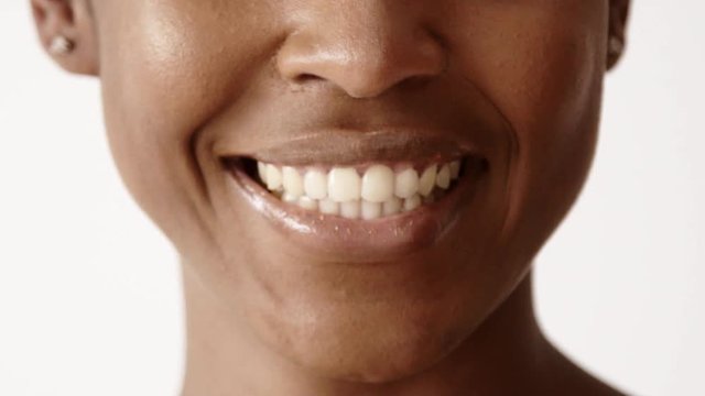 Moving focus closeup lips black girl starts smiling, happy showing healthy white teeth