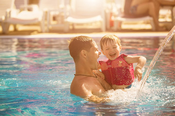 Father playing with son in pool
