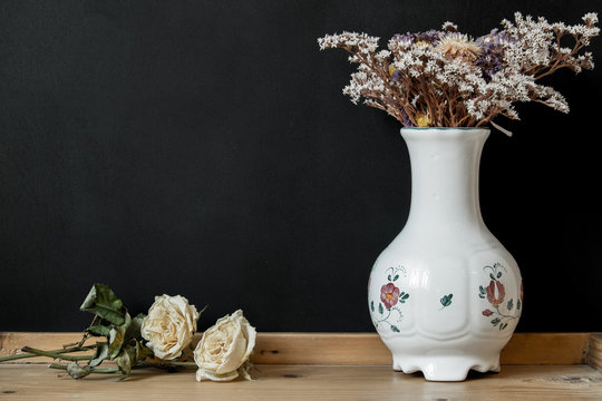 White Hungarian Herend porcelain vase with dry flowers on black background with copy space
