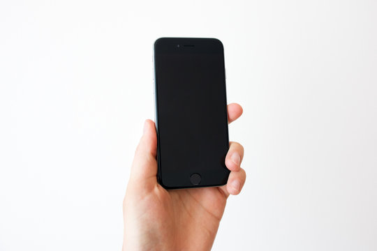 Hand holding black smartphone with blank screen