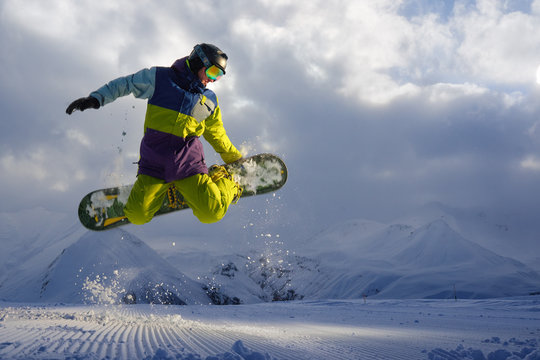 snowboarder does the jumping trick. snow scatters pieces