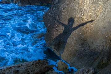 Girl dancing ballet shape shadow on a rock at the beach