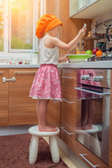 Obraz premium beautiful cute little girl with bonnet making pasta dough in kitchen