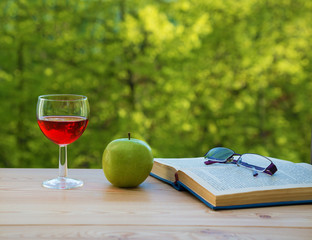 glass of wine green apple eyeglasses and book