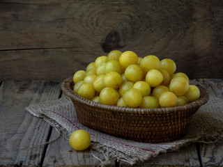 yellow plums in a basket on a wooden background