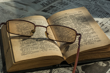Eyeglasses on the dictionary and newspaper