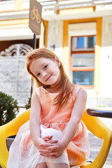 Beautiful little girl wear in fashion dress sitting in a cafe