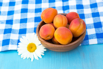 Ripe peaches in bowl on blue wooden background