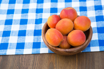 Ripe peaches in bowl on wooden background