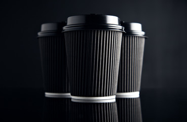 Luxury set of short cardboard paper cups closed with caps isolated on black and mirrored. Retail mockup presentation