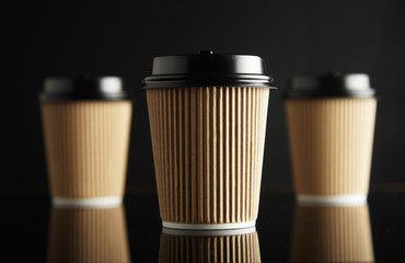 One focused in front of unfocused brown take away cardboard paper cups closed with caps isolated on...