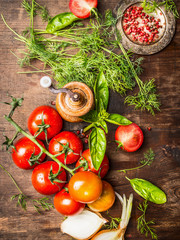 Fresh red tomatoes with green seasoning for tasty sauce cooking. Vegetarian cooking ingredients on rustic wooden background, top view