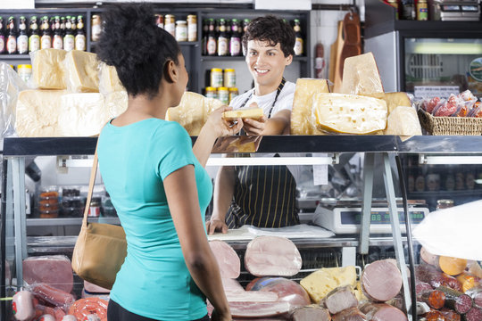 Smiling Salesman Selling Cheese To Female Customer