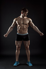 Fototapeta na wymiar Muscular bodybuilder guy doing posing over black background
