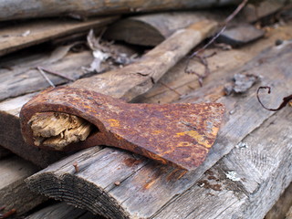 Used rusty axe with rotten haft on old wooden boards, closeup, shallow depth of field