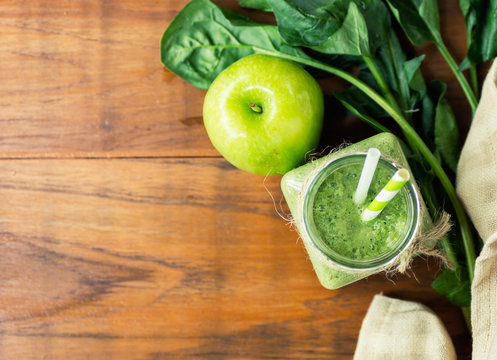 Homemade apple - spinach green smoothie on wooden kitchen table