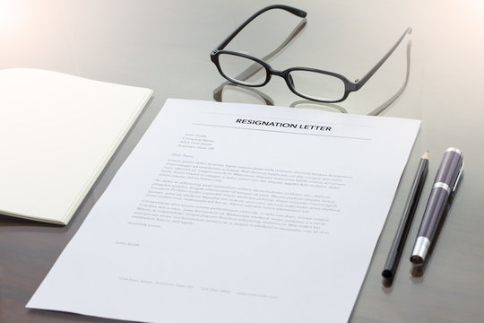 Resignation letter information with pen, pencil and glasses.